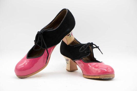 Zapatos de Flamenco profesional para mujer. Modelo Tientos. Nº37. Únicos, hechos a mano por Antonio García.  Abierto Con cordones. Fabricado en Charol rosa con ante negro. Tacón Semicarrete con flor pintada a mano Barnizado de 6,5 cm. Con clavos. Suela profesional cosida con filis de microfibra para amortiguar el golpe. Duración y sonido excepcional. Uno de los últimos zapatos fabricados por el artesano. 